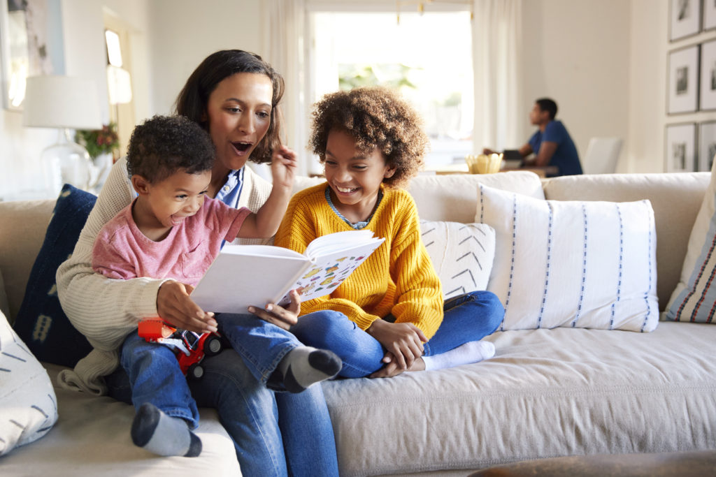 mom reading book to kids on couch