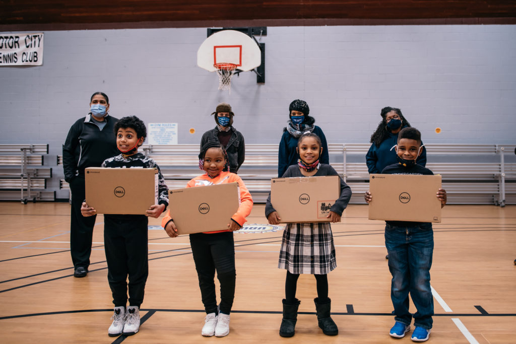 kids holding laptops in a gym