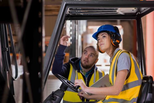 Young woman being trained to use a forklift