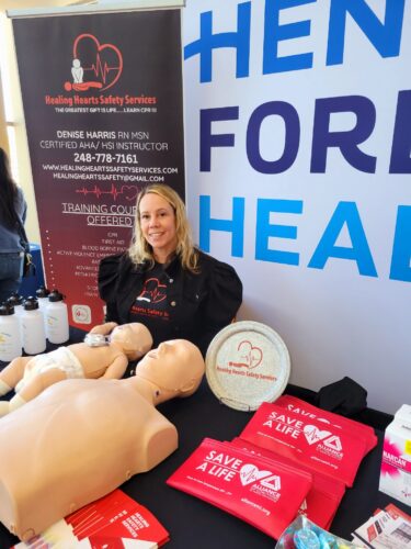Denise sits behind a table of CPR training materials
