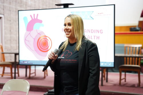 Denise smiles as she gives a presentation while holding a microphone