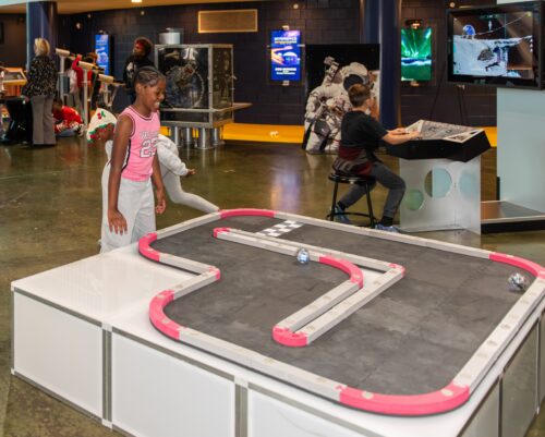 Student smiles above a robot racing track.