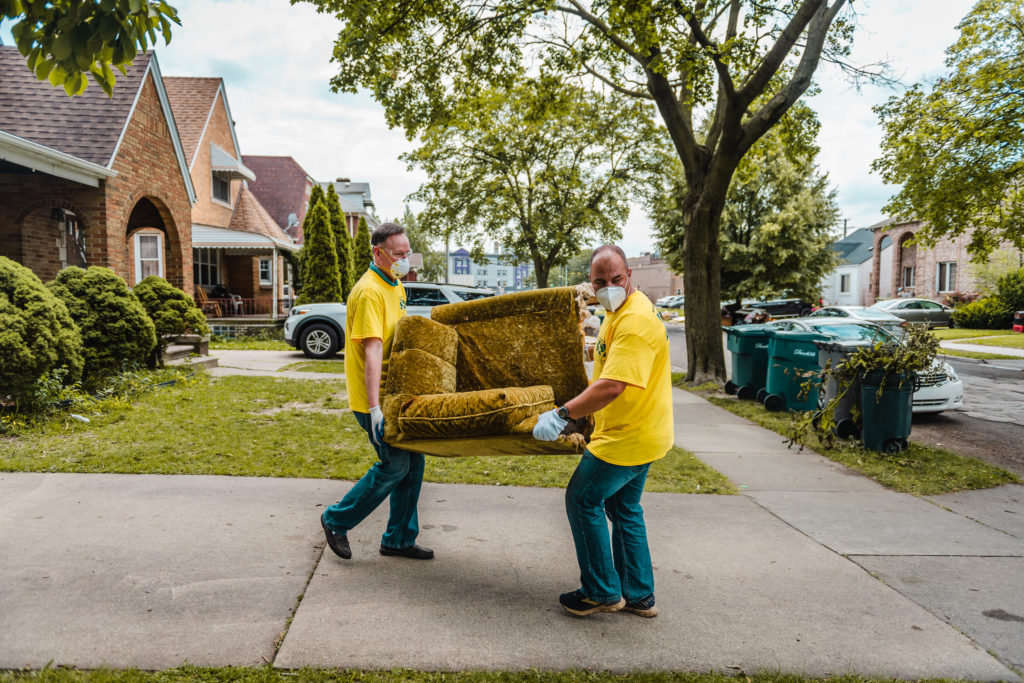volunteers carry furniture out to curb after flooding