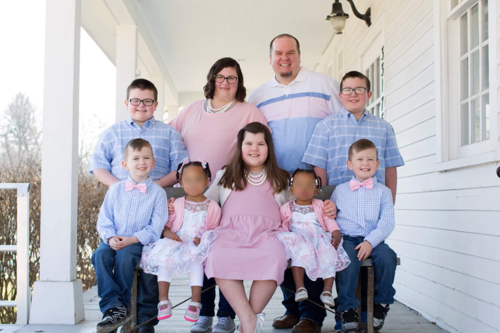 family of nine posing for photo on porch
